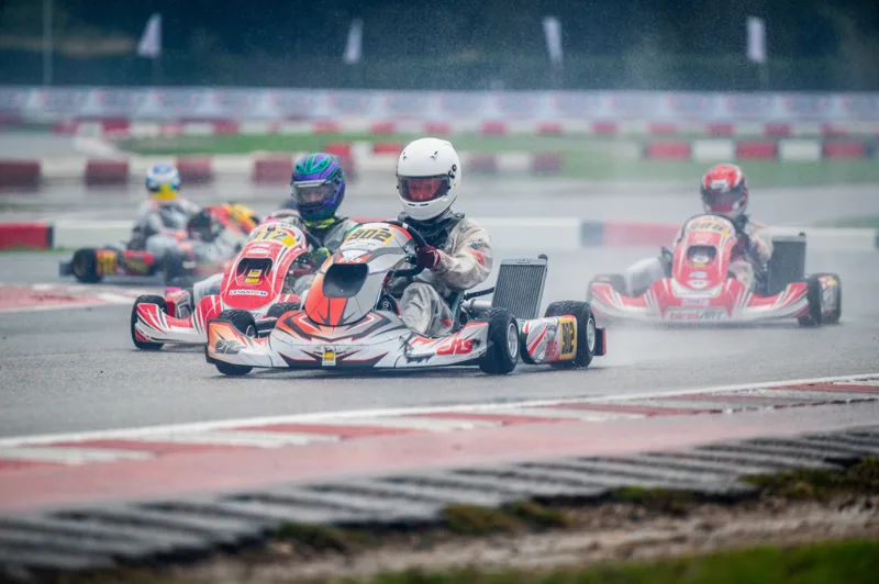Karting field in the rain with a driver in a white helmet in the EKS kart